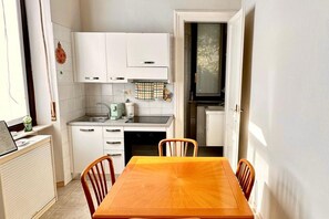 A compact kitchen with white cabinets, a dining table, and chairs. - Stunning apartment for two, just steps from Parco del Valentino – Turin. (Turin)