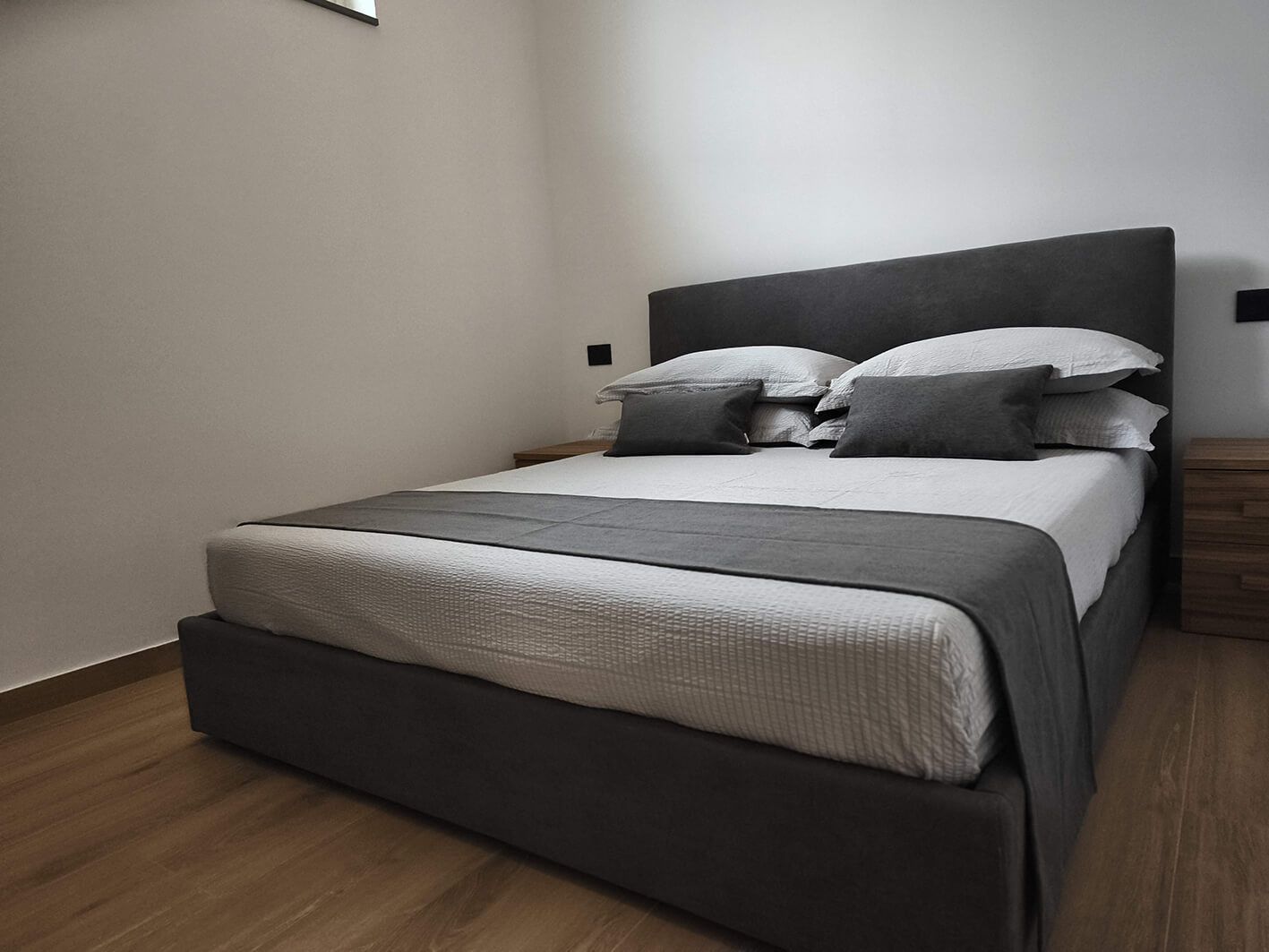 A modern bedroom with a bed, pillows, and a nightstand.