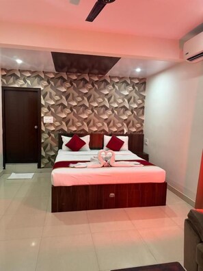 Una habitación de hotel con una cama, un ventilador de techo, una pared con diseño geométrico y una puerta.
