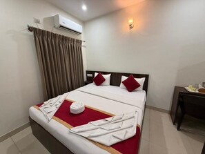 Habitación de hotel con cama, mesita de noche, aire acondicionado y lámpara de pared.