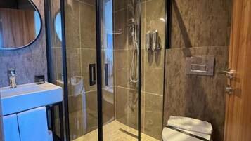 Un baño moderno con ducha de vidrio, inodoro y lavabo.