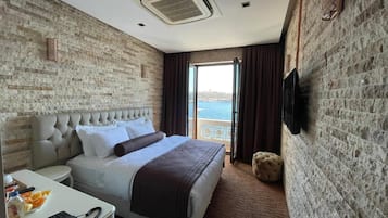 Ein Hotelzimmer mit Bett, Schreibtisch, Stuhl, Fernseher und Meerblick.