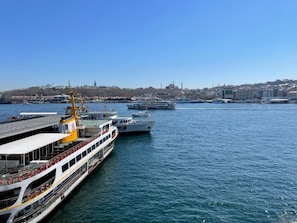 A harbor with multiple boats docked, a clear sky, and a cityscape in the background. - Weingart Port Seaside Hotel (Istanbul)