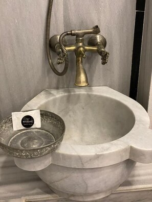 A marble sink with a brass faucet and a glass bowl. - Weingart Port Seaside Hotel (Istanbul)