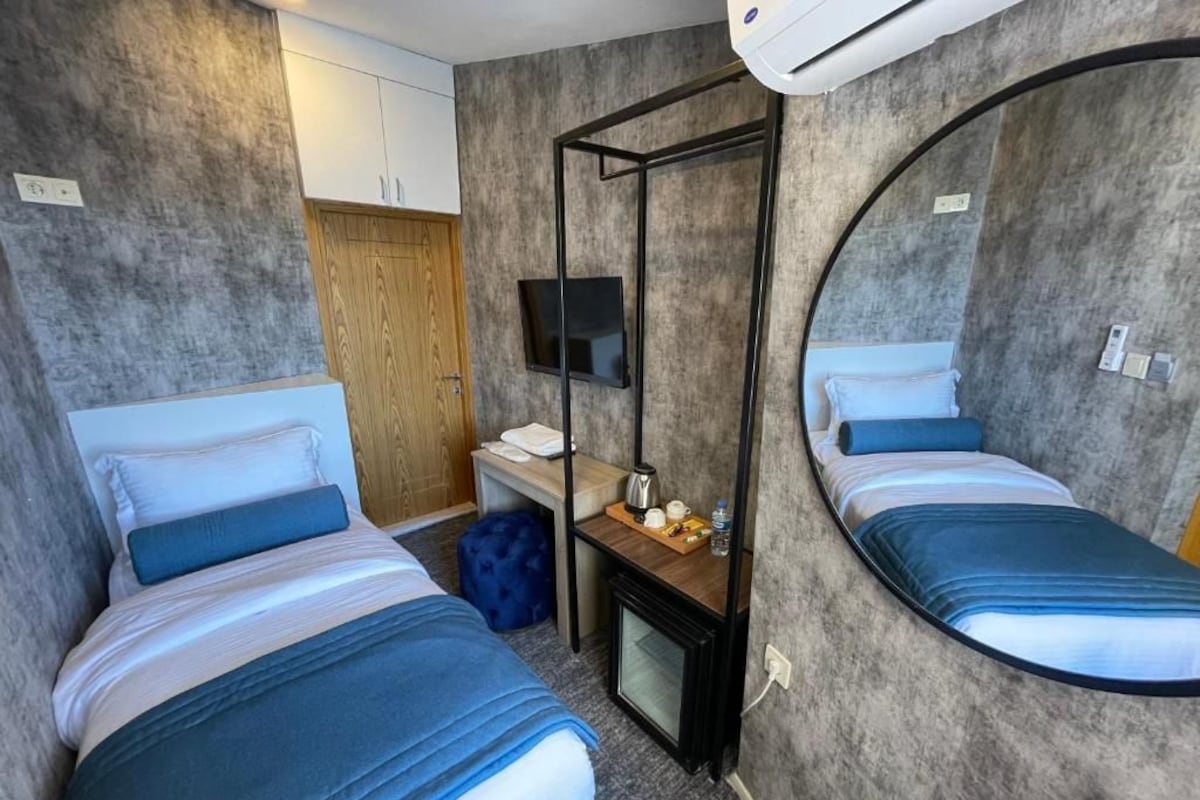Habitación de hotel con dos camas, un televisor, un escritorio con silla y un espejo.