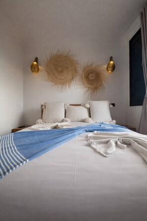 Ein Hotelzimmer mit einem Bett, Kissen, einem blauen Handtuch und Wandleuchten.