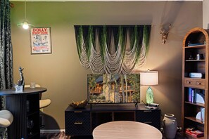 A room with a vintage poster, a decorative wall hanging, a lamp, a bookshelf, and a stone fireplace. - Romance , Free Tickets Everyday, Walk 2 Downtown (Gatlinburg)