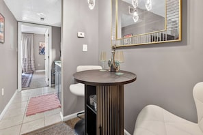 Een modern interieur met een ronde tafel, twee stoelen, een spiegel en een deur naar een andere kamer.