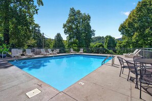 A rectangular swimming pool with a clear blue water surface, surrounded by a metal fence. There are lounge chairs and a table on the poolside. - Romance , Free Tickets Everyday, Walk 2 Downtown (Gatlinburg)