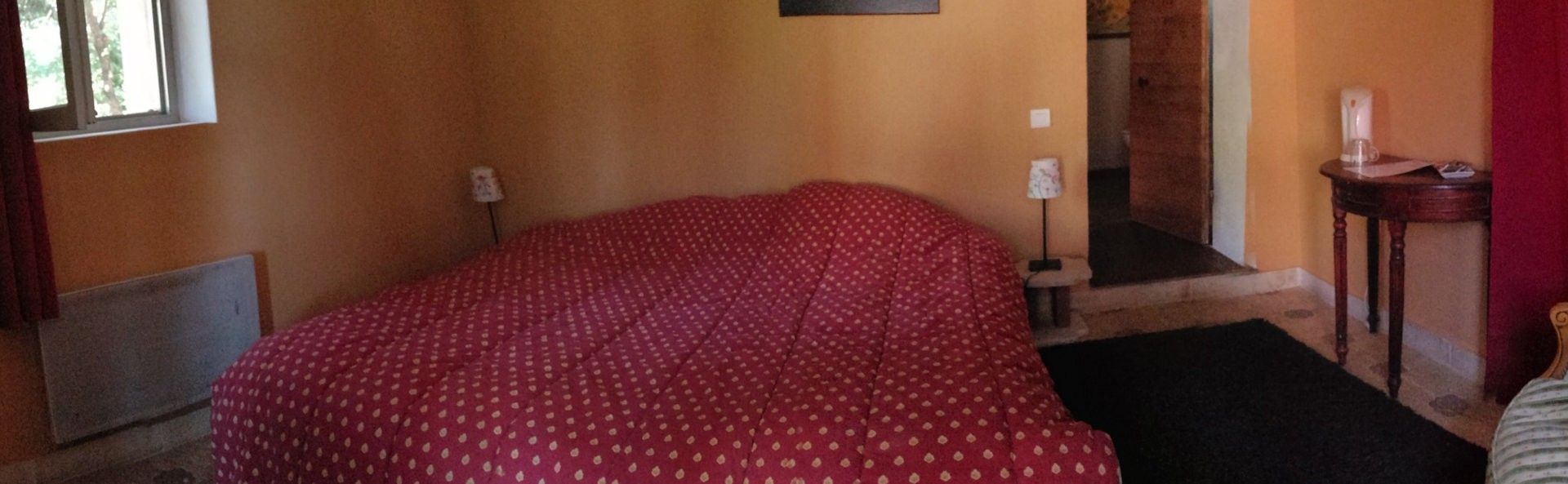 A room with a bed, a radiator, a lamp, and a small table with a candle.