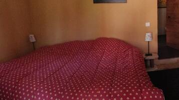 A room with a bed, a radiator, a lamp, and a small table with a candle.