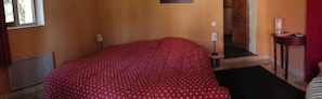 A room with a bed, a radiator, a lamp, and a small table with a candle.