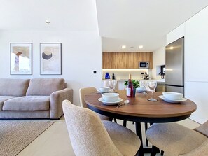 Ein modernes Wohnzimmer mit Essbereich, einer Couch und einem für eine Mahlzeit gedecktem Tisch.