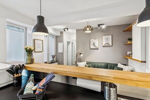 A modern kitchen with a wooden countertop, a hanging light fixture, and a view into the dining area. - City Living—Stylish Living in St. Wendel (Sankt Wendel)