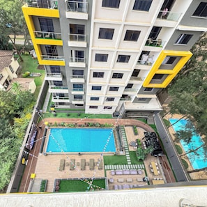 A multi-story residential building with balconies, a swimming pool, and a landscaped garden area. - Kilimani Nairobi Luxury Stay | Pool, Gym, Sauna | 1 bedroom (Nairobi)