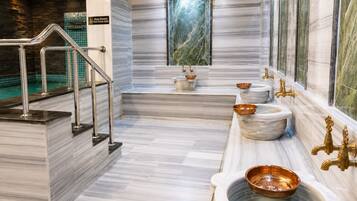 Une salle de bain moderne avec un sol en marbre, une douche en verre et plusieurs lavabos dotés de cuves en cuivre.