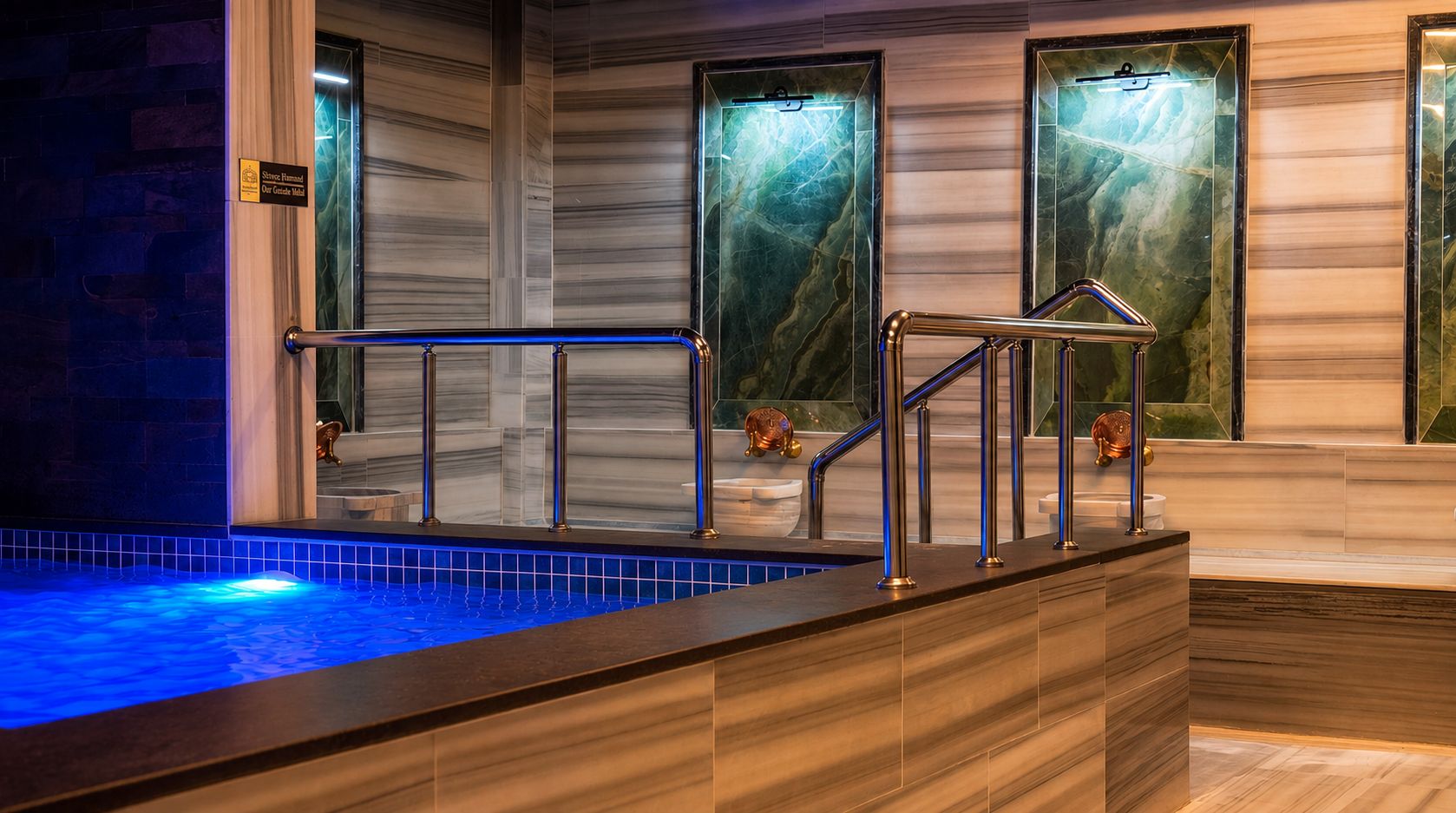 A spa area with a hot tub, wooden flooring, and marble walls.