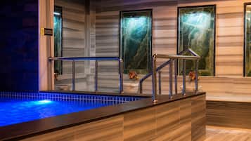 A spa area with a hot tub, wooden flooring, and marble walls.
