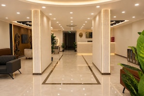 Un hall de hotel con mostrador de recepción, zona de estar y diseño moderno.