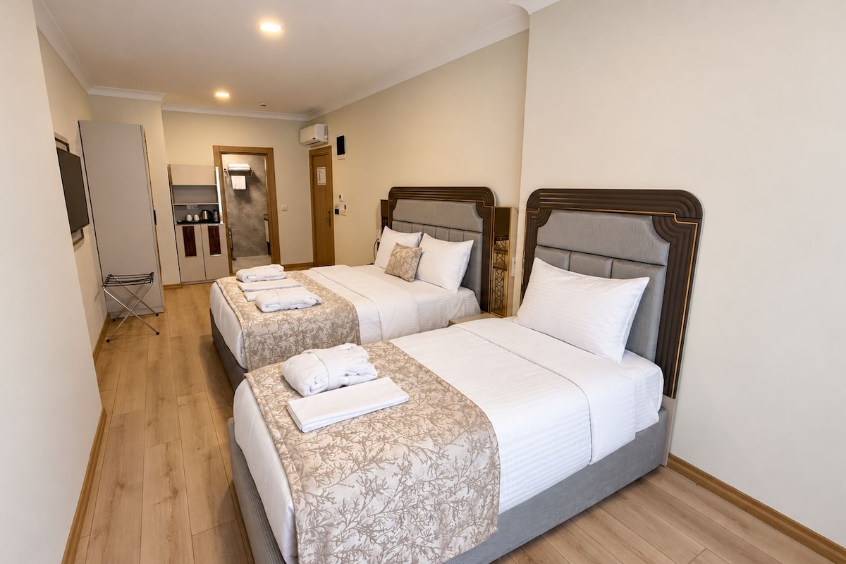 Habitación de hotel con dos camas, kitchenette y piso de madera.