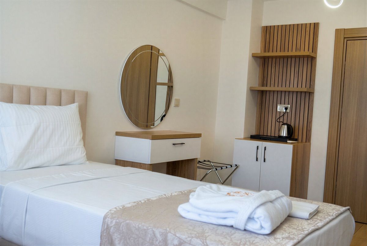 Une chambre d’hôtel avec un lit, une table de chevet, un miroir, une armoire et une serviette sur le lit.