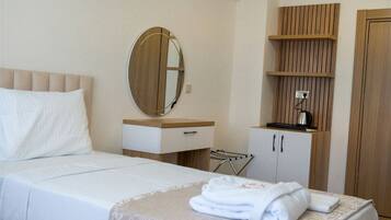 Une chambre d’hôtel avec un lit, une table de chevet, un miroir, une armoire et une serviette sur le lit.