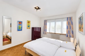 Ein Hotelzimmer mit einem Bett, einem Kleiderschrank, einem Fenster mit Vorhängen und zwei Bildern an der Wand.
