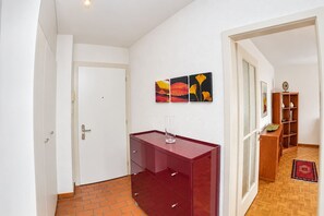 Ein Flur mit einem roten Schrank, einer Tür und einer Wand mit drei gerahmten Kunstwerken.