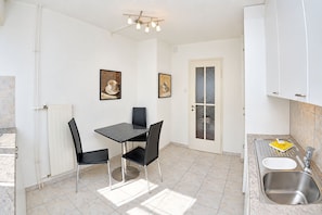 A compact kitchen with a dining table, chairs, a sink, and cabinets. - Queen-Size Bed / Private Balcony / Central - Ghost 11 (Zürich)