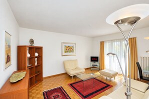 Ein modernes Wohnzimmer mit einer Couch, einem Sessel, einem Couchtisch und einem Fernseher, der Netflix anzeigt.