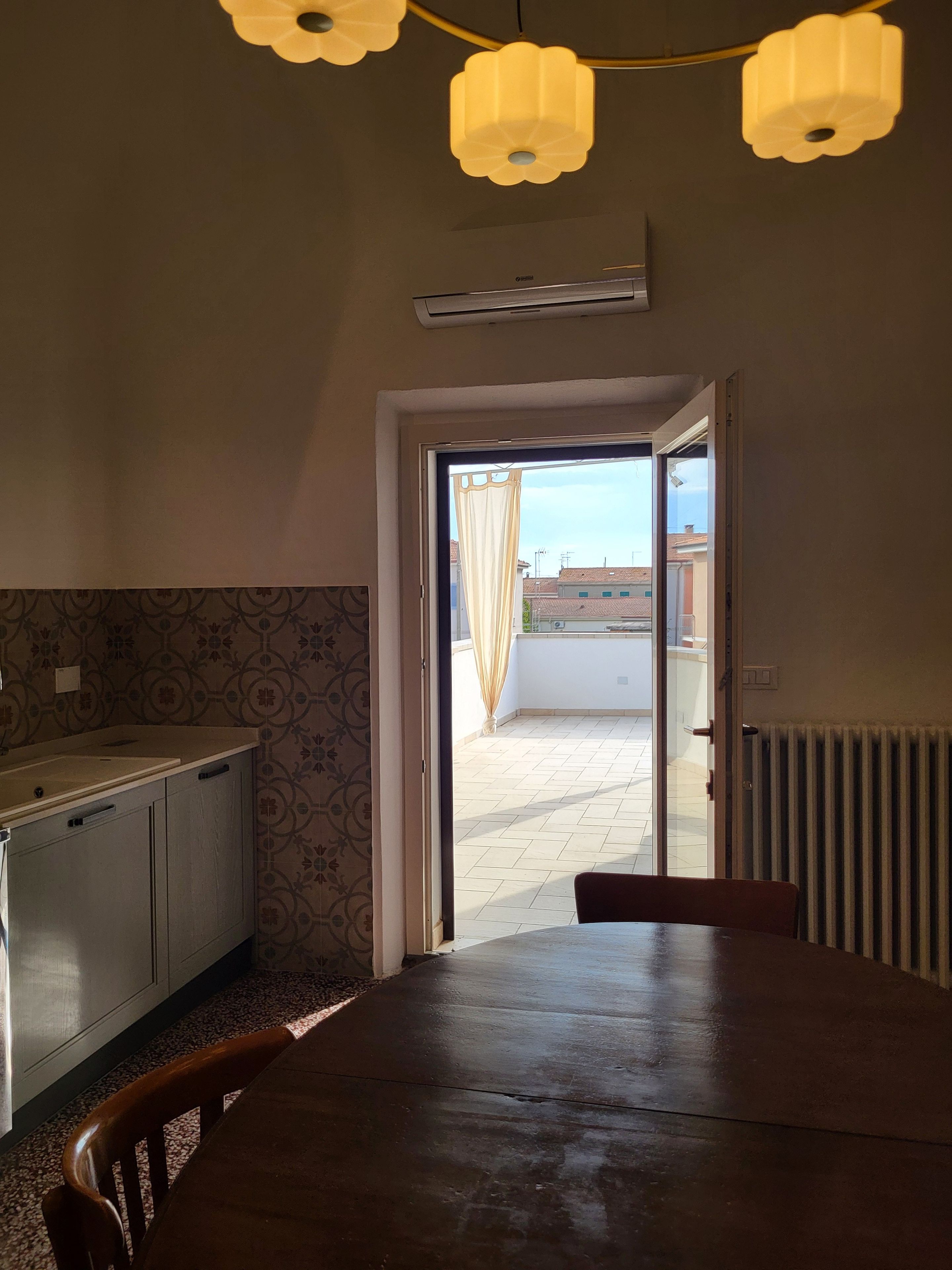 A kitchen with a dining table, a radiator, and a view of the outside.
