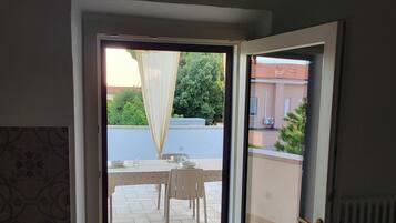 A room with a sliding glass door leading to an outdoor patio area with a table and chairs.
