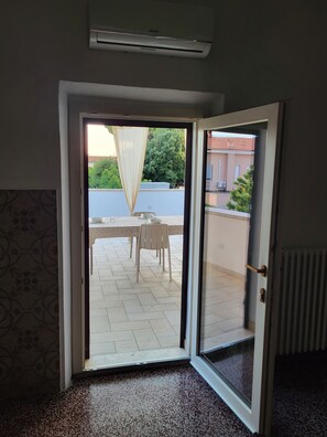 A room with a sliding glass door leading to an outdoor patio area with a table and chairs.