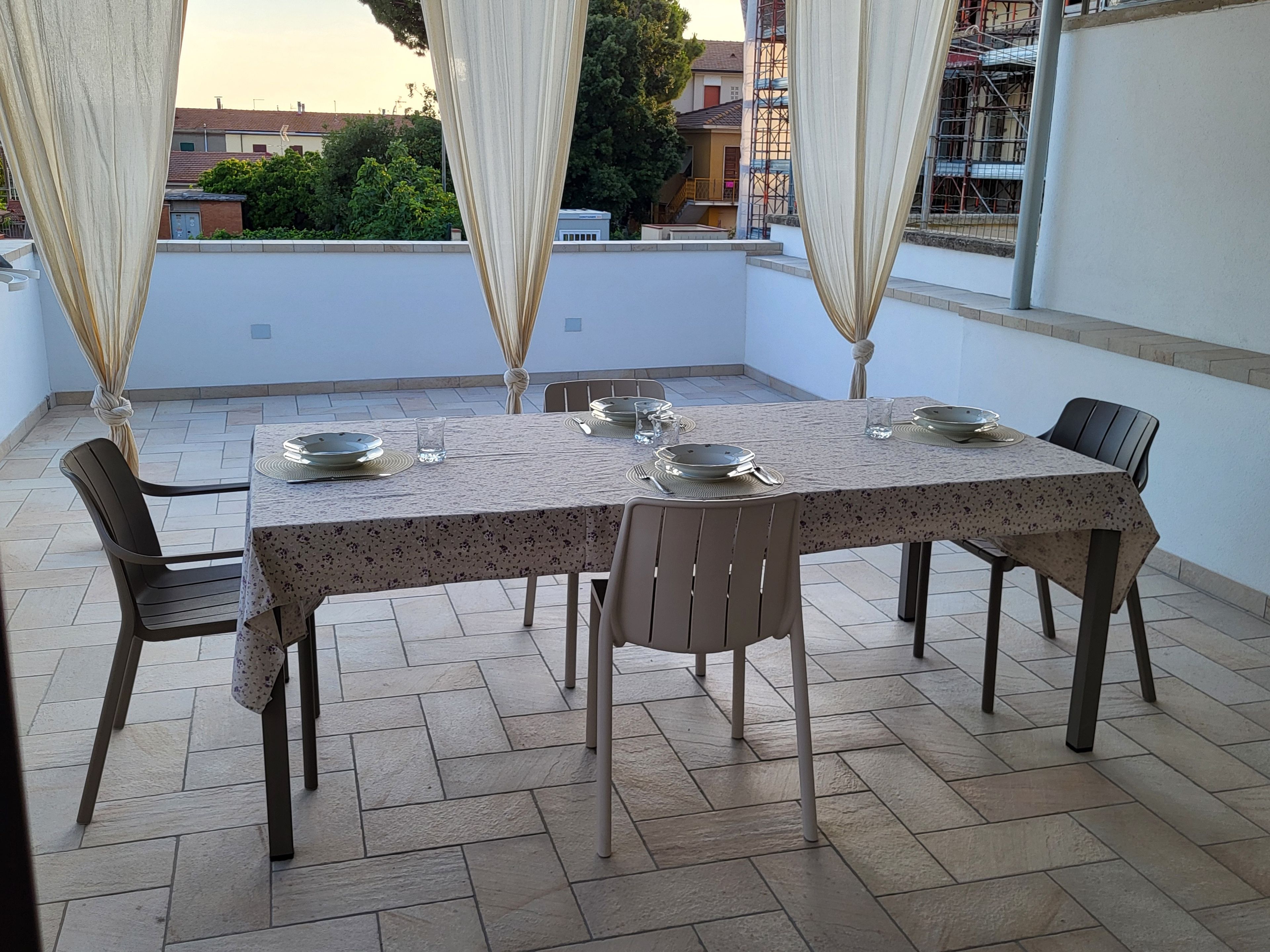 Ein Essbereich mit Tisch für vier Personen, Stühlen und Blick auf die umliegenden Gebäude.