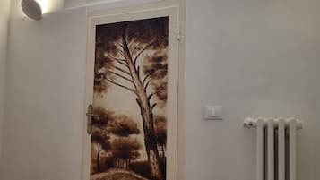 A door with a landscape mural, a radiator, and a window with a view.