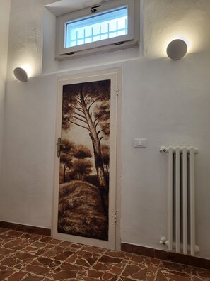 A door with a landscape mural, a radiator, and a window with a view.