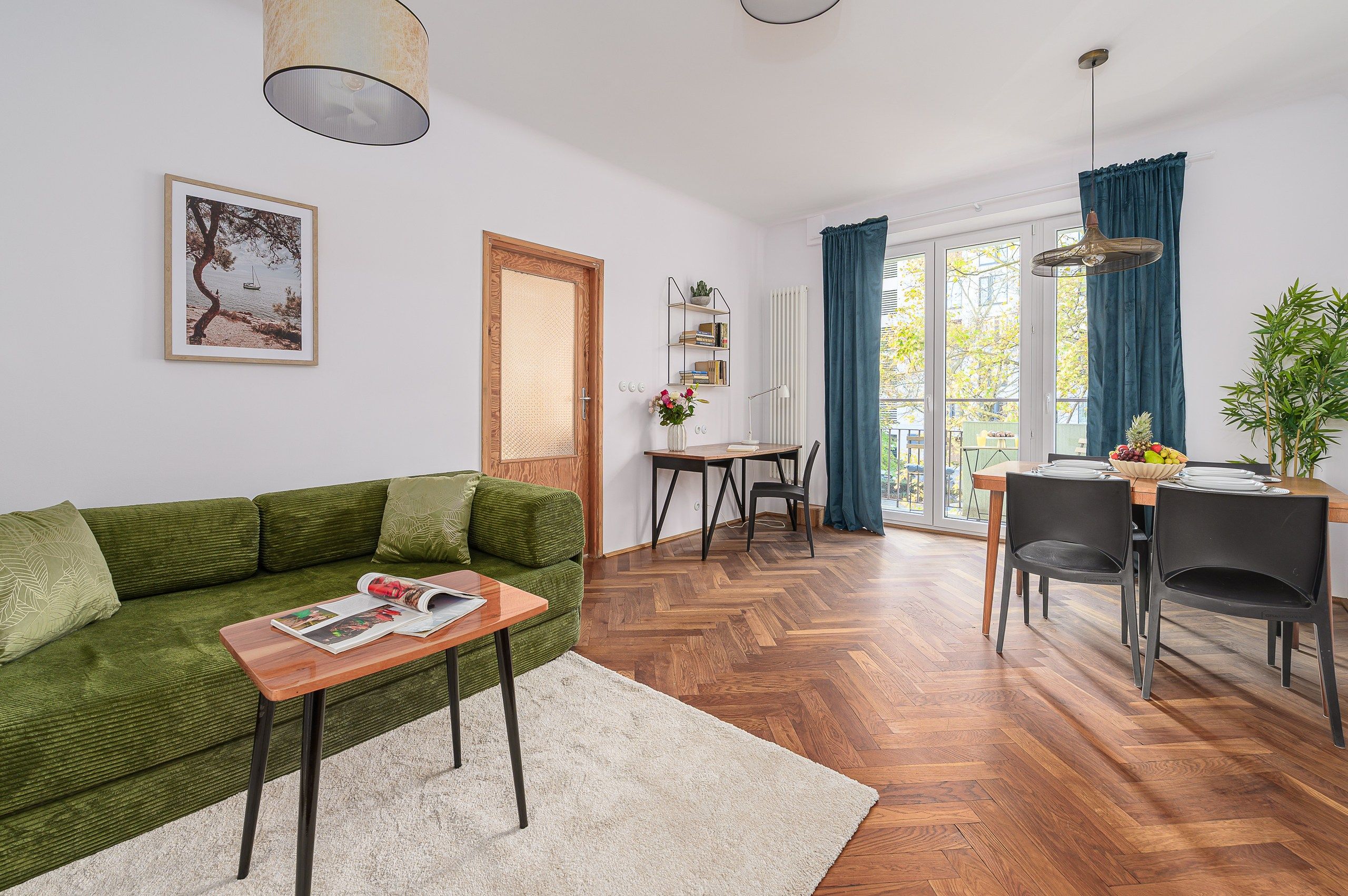 Una sala de estar con un sofá verde, una mesa de centro de madera y un comedor con mesa y sillas.
