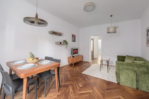 A modern living space with a dining area, a green sofa, and a TV displaying 'NETFLIX'. - Lumina 2BR Apart near Center of Warsaw (Warszawa)