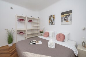 A bedroom with a bed, a wardrobe, a painting, and a plant. - Lumina 2BR Apart near Center of Warsaw (Warszawa)