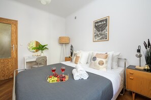 Ett hotellrum med en säng, ett sängbord, en lampa och ett inramat konstverk på väggen.