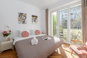 Ett modernt sovrum med en stor säng, en balkong med utsikt och två konstverk på väggen.