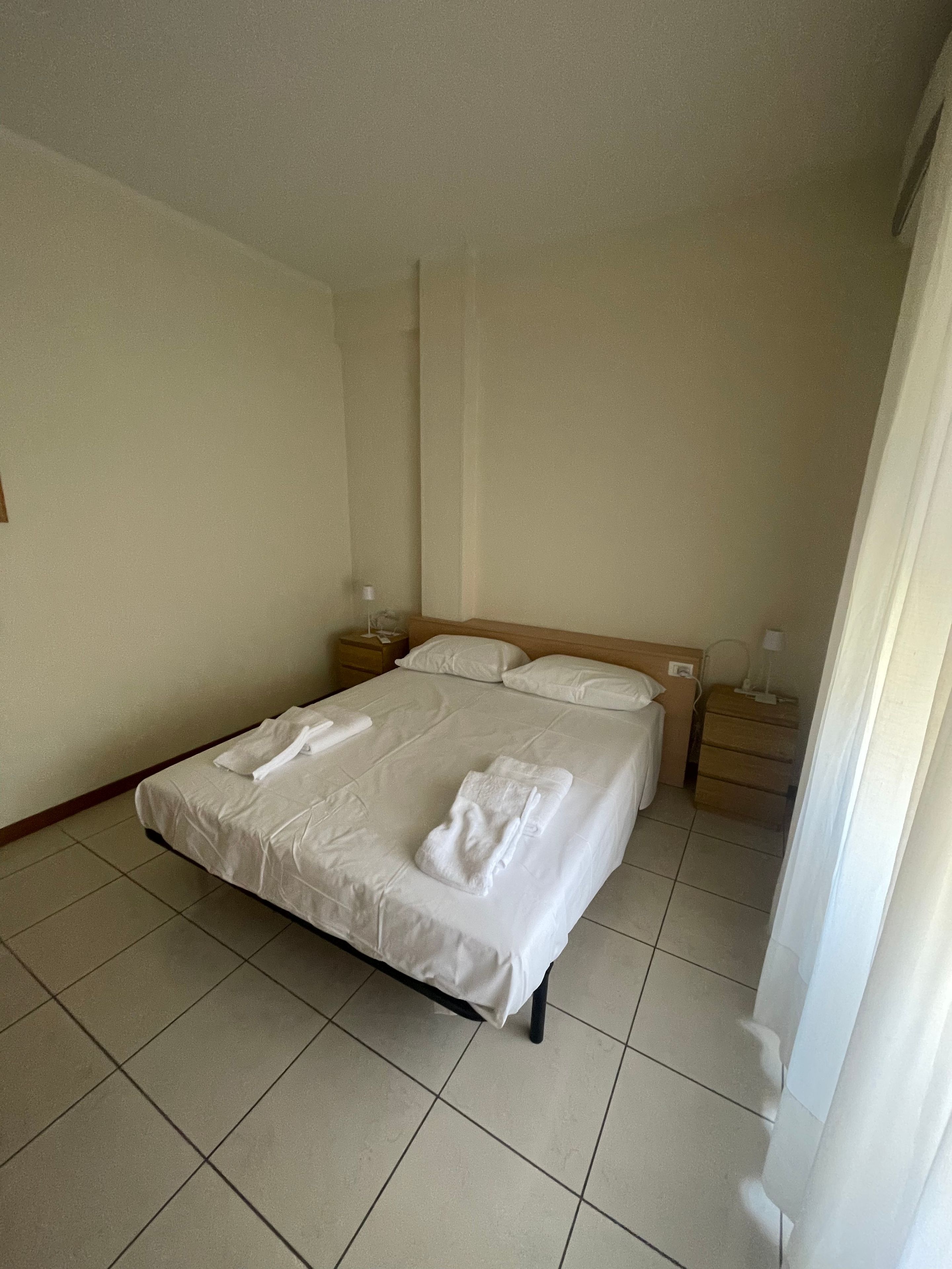 Ein Hotelzimmer mit einem Bett, zwei Nachttischen und einem kleinen Schreibtisch.