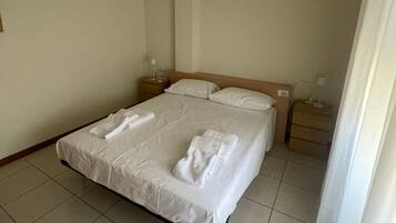 Ein Hotelzimmer mit einem Bett, zwei Nachttischen und einem kleinen Schreibtisch.