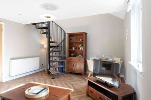 A modern living room with a spiral staircase, wooden furniture, a television, and a dining area. - Glasgow City Centre, Nr Central Station, Private Parking (Glasgow City)