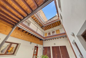 A multi-level courtyard with wooden beams, balconies, and a clear sky view. - Apartment 'Galindo II Center Premium Suites' with Private Terrace, Wi-Fi and Air Conditioning (Sevilla)