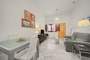 A modern living room with a dining area, a grey sofa, a TV, and a lamp. - Apartment 'Galindo II Center Premium Suites' with Private Terrace, Wi-Fi and Air Conditioning (Sevilla)