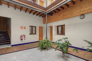 Een ruime binnenplaats met een houten plafond, betegelde vloer en potplanten.