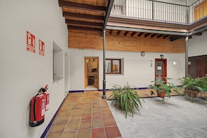 A covered outdoor area with a tiled floor, wooden beams, a fire extinguisher, and potted plants. - Apartment 'Galindo II Center Premium Suites' with Private Terrace, Wi-Fi and Air Conditioning (Sevilla)