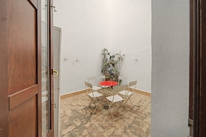 A small patio area with a table and four chairs, a potted plant, and a door leading to another room. - Apartment 'Galindo II Center Premium Suites' with Private Terrace, Wi-Fi and Air Conditioning (Sevilla)