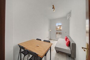 A compact living space with a dining area, a sofa, and a view through a door. - Apartment 'Macarena Seville Premium Suites' with Private Terrace and Air Conditioning (Sevilla)